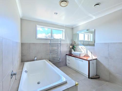a bathroom with a tub and a sink and a mirror at Luxury Lake View farm stay with spa pool in Rotorua