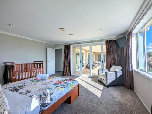 a bedroom with a bed and a chair and a window at Luxury Lake View farm stay with spa pool in Rotorua