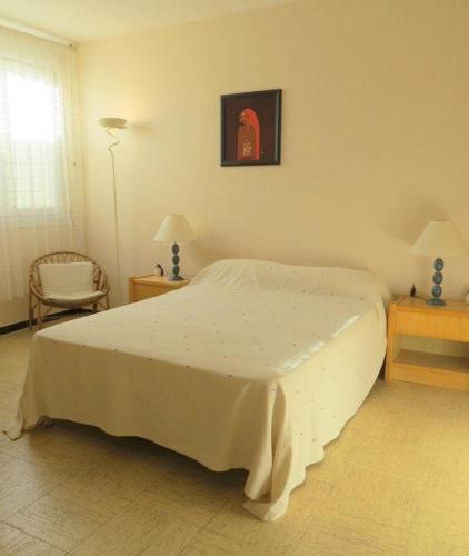 une chambre avec un lit blanc et une chaise dans l'établissement Agréable Maison Familiale 100 m de la plage 6AVAN5, au Barcarès