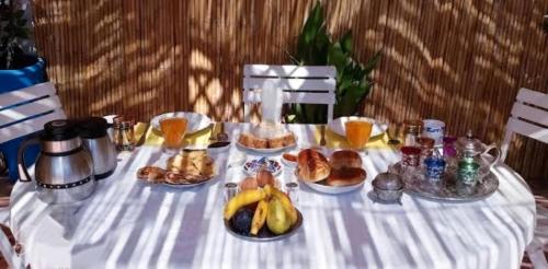 una mesa con un mantel blanco con alimentos para el desayuno. en Fes Antique Hostel, en Fez