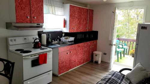 a kitchen with red cabinets and a sink and a stove at Quiet cozy apartment next to highway wifi+netflix in Edmundston