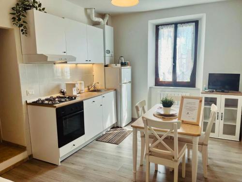 a kitchen with white cabinets and a table and a stove at La casa di Tommy in Monsummano