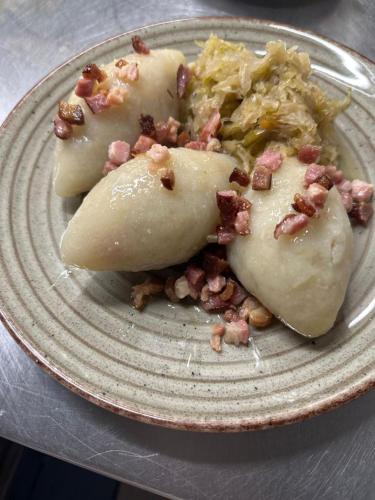 a plate of food with potatoes and bacon on it at Hotel Kresowianka in Konin
