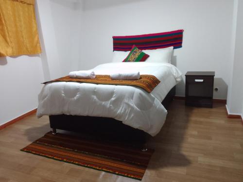 1 dormitorio con 1 cama con mantas y almohadas blancas en Incas Town Inn, en Cusco