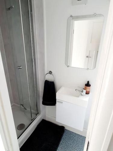 a white bathroom with a shower and a sink at Fabulous family house next to the beach in Nottage