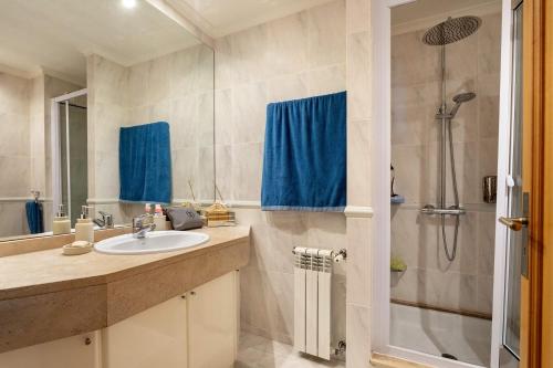 a bathroom with a sink and a shower with blue curtains at Oporto, sea view and marina in Canidelo