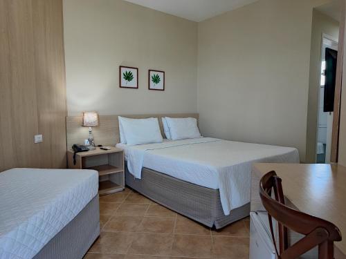 a bedroom with two beds and a table with a chair at Hotel Coral Beach in Tamandaré