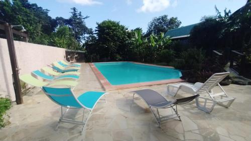 a group of chairs and a swimming pool at Gite bagatelle classé 2 étoiles in Sainte-Rose