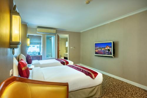 a hotel room with two beds and a tv at Nasa Bangkok in Bangkok
