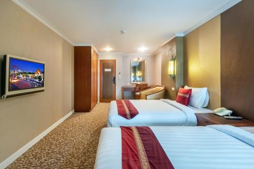 a hotel room with two beds and a television at Nasa Bangkok in Bangkok