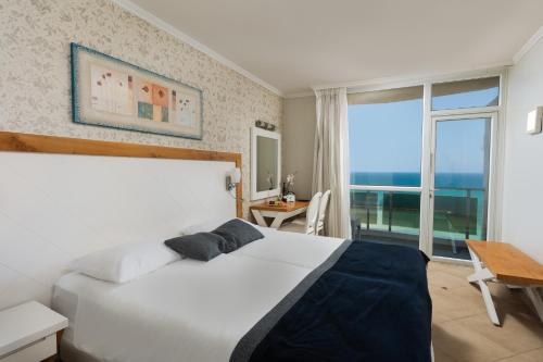 a bedroom with a white bed and a large window at Residence Hotel in Netanya