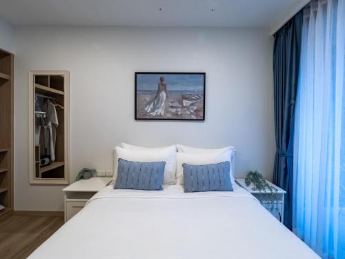 a white bed with blue pillows in a bedroom at Comfortable apartments in Laguna Skypark in Phuket Town