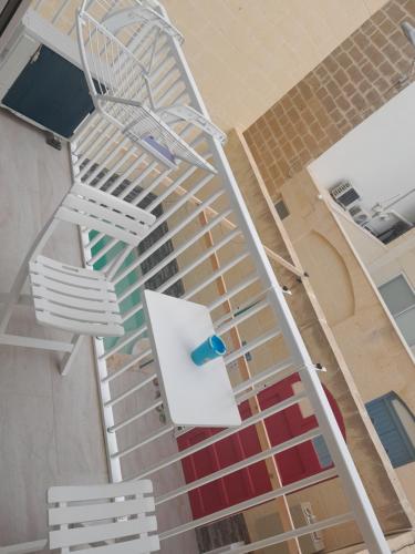 a white spiral staircase in a building with two chairs at C'Est La Vie in Xagħra