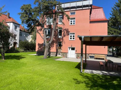 einen grünen Hof mit einem Gebäude und einem Baum in der Unterkunft Apartment-Haus Landeskrone in Dresden