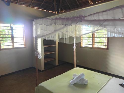 a bedroom with a canopy bed with towels on it at Villa Métisse in Nosy Be