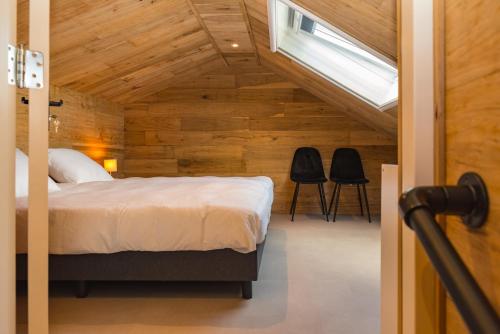 1 dormitorio con 1 cama y 2 sillas negras en Sallands huisje, en Haarle