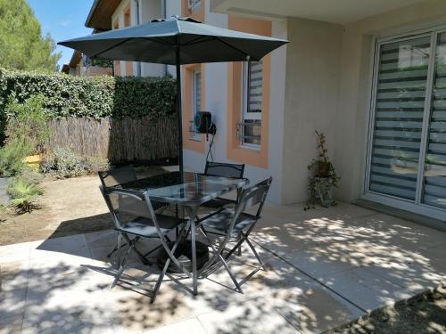 een tafel en stoelen met een parasol op een patio bij Les Portes du Soleil in Grabels