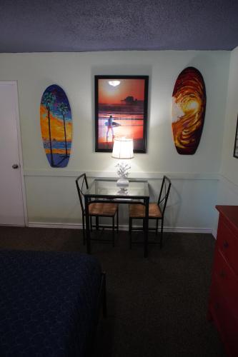 a room with a table and four surfboards on the wall at Huntington Surf Inn in Huntington Beach