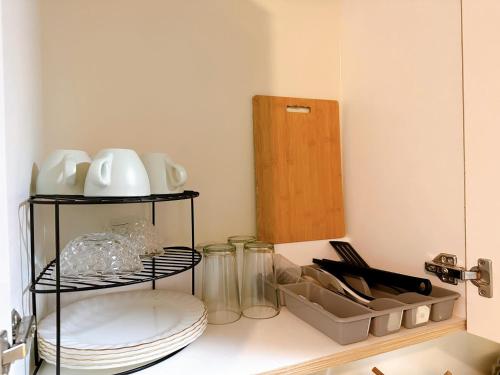 a kitchen counter with a shelf with plates and utensils at Luxury Suites at Brenthill Baguio City in Baguio