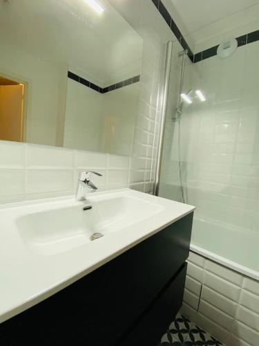 une salle de bain blanche avec un lavabo et une douche dans l'établissement Super cozy appartement, à Marquette-lès-Lille