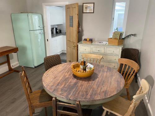 a kitchen with a wooden table with chairs and a refrigerator at Windsor Cottage: Cosy, Charming, Full of Character in Windsor