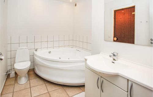 La salle de bains blanche est pourvue d'une baignoire, de toilettes et d'un lavabo. dans l'établissement Amazing Home In Aabenraa With Kitchen, à Danland Løjt