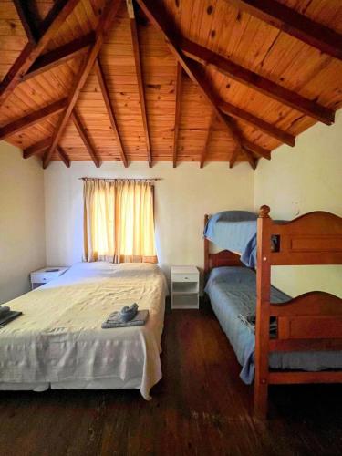 1 Schlafzimmer mit 2 Betten und Holzdecke in der Unterkunft Calida cabaña in Ushuaia
