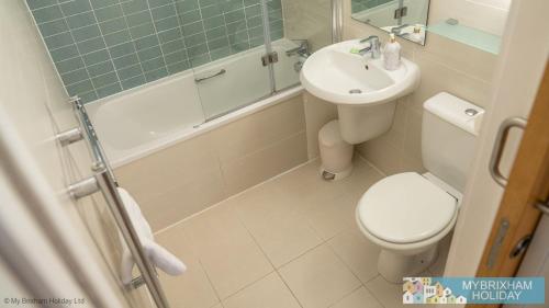 a bathroom with a sink and a toilet and a tub at Plover 2 - The Cove in Brixham