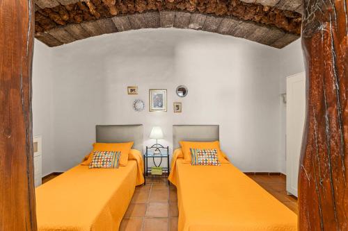 2 Betten mit orangefarbenen Kissen in einem Zimmer in der Unterkunft Apartamento rural Los Roferos in Guatiza