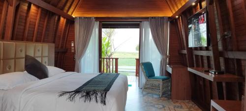 sypialnia z łóżkiem i przesuwnymi szklanymi drzwiami w obiekcie Kori Maharani Villas & Resort w mieście Keramas