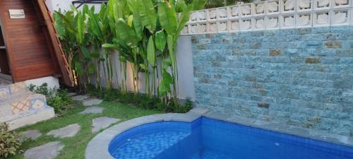 a swimming pool in a yard next to a fence at Kori Maharani Villas & Resort in Keramas