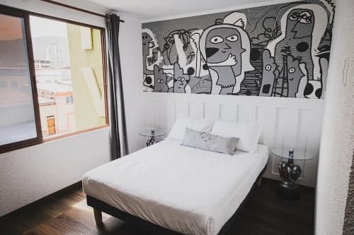 um quarto com uma cama branca e uma pintura na parede em hotel velero cavancha em Iquique