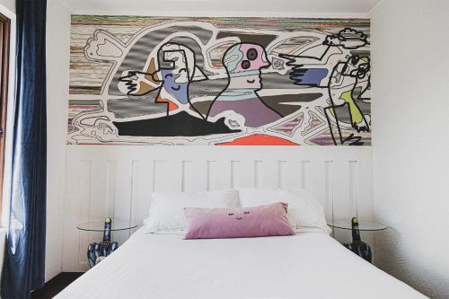 a bedroom with a white bed with a painting on the wall at hotel velero cavancha in Iquique