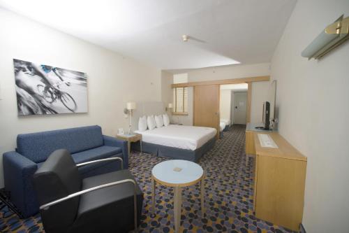 a hotel room with a bed and a couch at Sport Club by Isrotel Collection in Eilat