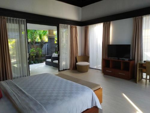 a bedroom with a bed and a flat screen tv at Kori Maharani Villas & Resort in Keramas