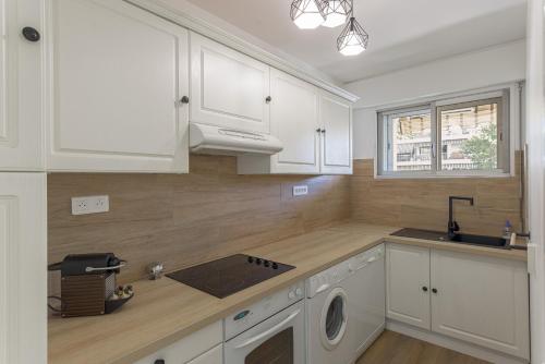 une cuisine avec des armoires blanches, un évier et une cuisinière dans l'établissement Cosy studio - Centre Cannes - Terrasse - Clim - Wifi, à Cannes
