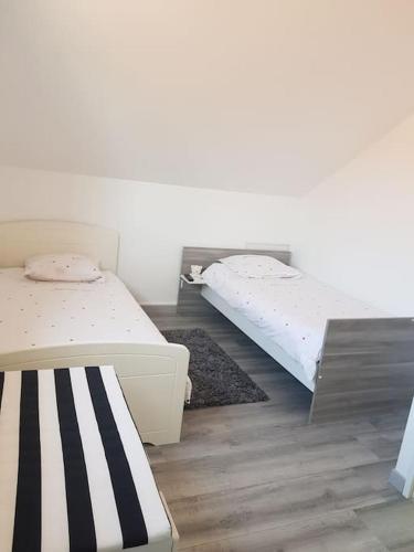 two beds in a room with wooden floors at Maison avec terrasse à 15 minutes de Disney in Nanteuil-lès-Meaux