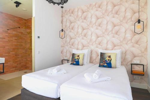 a bedroom with two white beds and a pink wall at Boutique Hotel Maldegem in Vlissingen