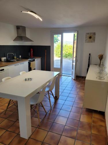 - une cuisine avec une table blanche et des chaises blanches dans l'établissement Bas de villa F3 proche Ajaccio, à Cuttoli-Corticchiato