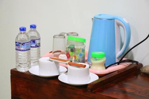 einem Holztisch mit Tassen und Wasserflaschen in der Unterkunft Panoramic Royal Villa in Sigiriya