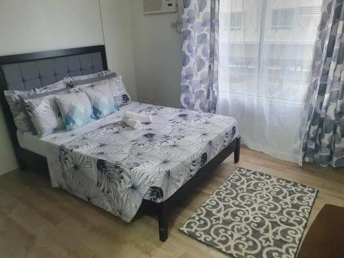 een slaapkamer met een bed, een raam en een tapijt bij Bacolod Mesavirre Condominium in Bacolod