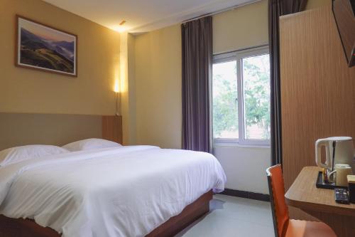 um quarto de hotel com uma cama e uma janela em City Hotel Mataram em Mataram