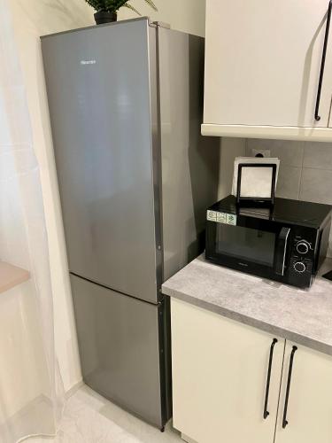 a stainless steel refrigerator in a kitchen with a microwave at James Dean apartment - next to Nivy Bus station & Mall (Free parking on the weekend) in Bratislava