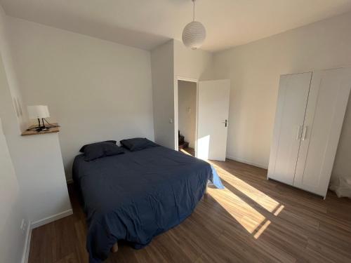 une chambre avec un lit dans une pièce blanche dans l'établissement Maison de village, à Saint-Pierre-des-Nids