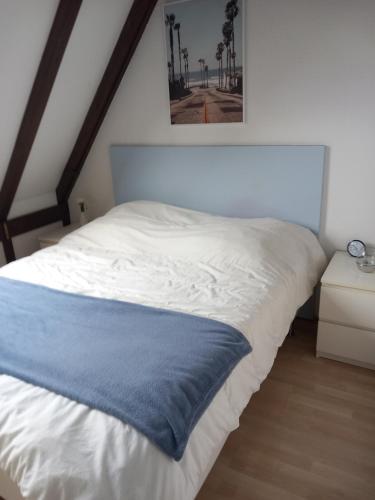 ein weißes Bett mit einer blauen Decke darüber in der Unterkunft Au tonneau bleu in Lembach