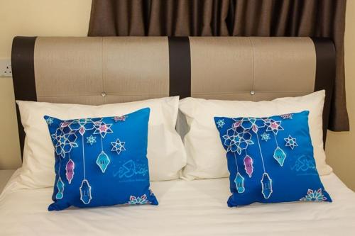 a bed with blue pillows and two blue pillows at Southern Tip Hotel in Pontian Kecil