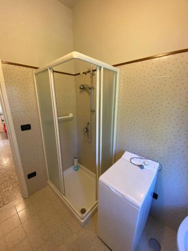 baño con ducha y nevera blanca. en Arcobalenotoscano Convivio, en Pescia