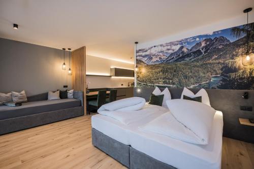 a bedroom with a large bed and a couch at Montanaris Alpine - Active - Relax in Villabassa