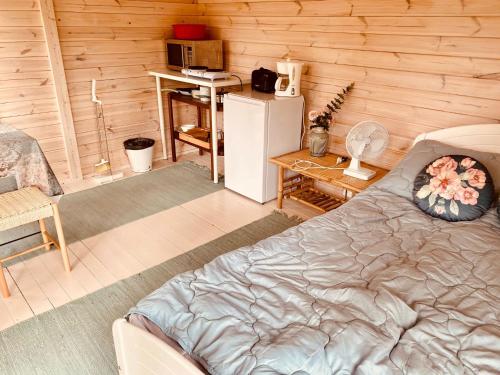 Lemmenjoen Lumo - Nature Experience & Accommodation في Lemmenjoki: غرفة بسرير ومكتب وثلاجة