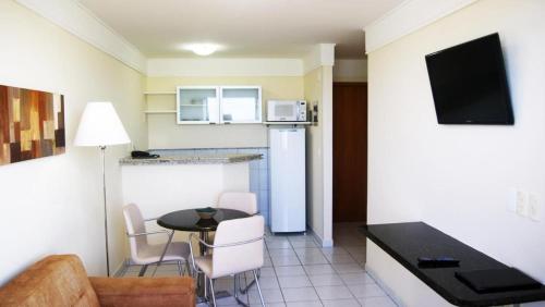 a small living room with a table and a kitchen at CJC Short Stay Natal in Natal